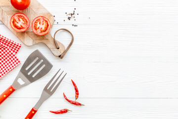 Picnic flatlay. Steel barbecue utensils with tomatoes and greens, top view