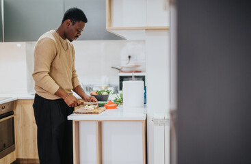 A person is chopping ingredients on a countertop, focused on preparing a vegetable-filled meal, situated in a contemporary kitchen environment with a clean, organized style.