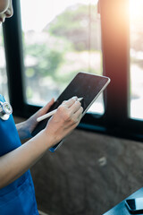Healthcare worker using a tablet with a stylus in a bright office, showcasing modern medical...