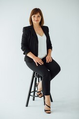 Confident businesswoman sitting on stool in studio setting