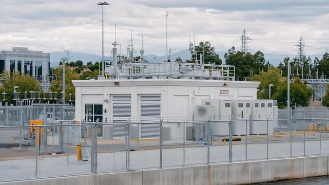 Explore a secure, robust data center with reinforced concrete, backup generators, and security fencing, set against an overcast sky.