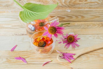 Medicinal herbal tea from echinacea flowers. Tea in a glass cup with fresh echinacea flowers on a wooden background.