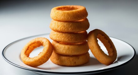 A tall stack of golden deep-fried onion rings served on a white plate.