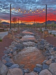 String lights illuminate a river during a scenic and vibrant sunset