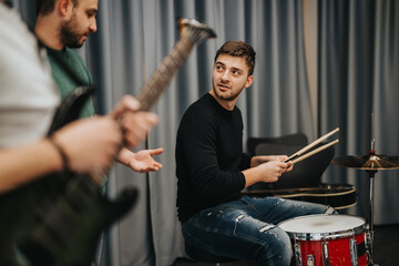 Two musicians collaborate in a studio setting, with strong communication during a practice session combining drums and guitar for music creation.