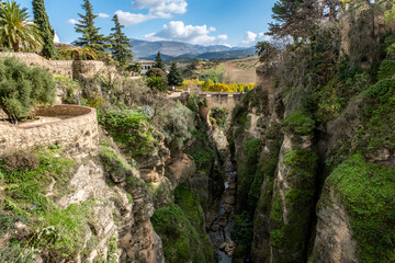 The Puente Viejo, Old Bridge, beside the ancient city walls of Ronda, southern Spain, with a scenic view of the surrounding Serranía de Ronda mountain range of Andalucia.