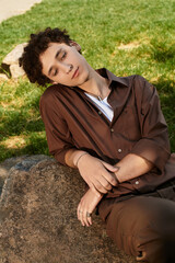 Stylish young man relaxing in a green park during a sunny summer day
