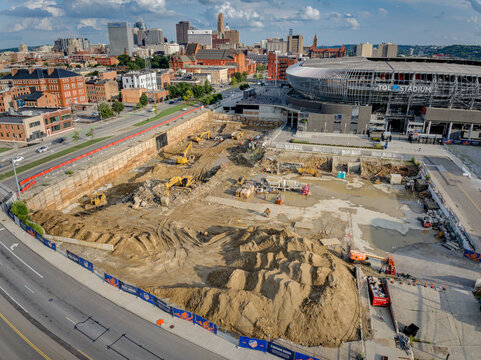 Cincinnati, United States - 18 July 2025: Aerial view of construction site with heavy machinery against the backdrop of the cityscape and stadium.