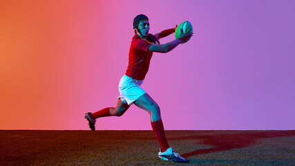 Woman striking a dynamic rugby pose against a colorful studio background. Concept of sprinting move, bold action frame, future-ready athlete