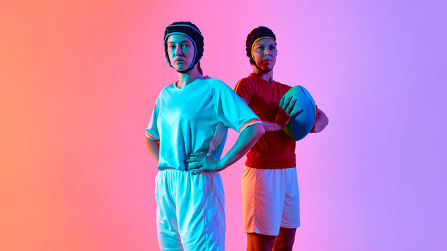 Pair of rugby athletes posing confidently against vivid background hues. Concept of team spirit, duo presentation, sports togetherness, athlete promo