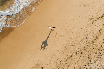 Woman Doing Yoga on Sandy Beach with Long Shadow, Aerial View