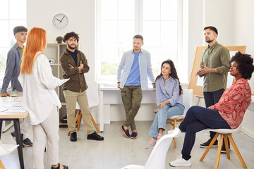 Group of business people chatting on a meeting standing in circle in office. Company employees...