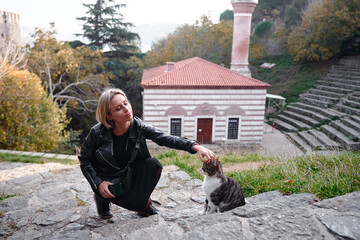 Woman Petting a Cat in a Scenic Outdoor Historical Site