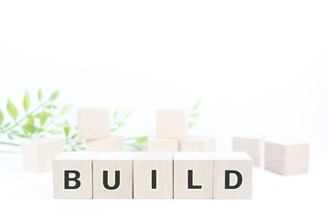 木製ブロックで構築を表すBUILDの文字と背景の積み木