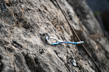 Quickdraw with rope in a bolt on the rock for lead climbing in daylight in nature, close-up sport equipments outdoors, rock climbing gear