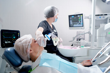 Doctor making anesthesia while female patient lying in dentist chair