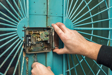 Closeup of professional locksmith installing or repairing mortise lock. Aligning lock components on...