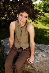 Stylish young man enjoys a sunny day in a vibrant green park, embracing summer fashion