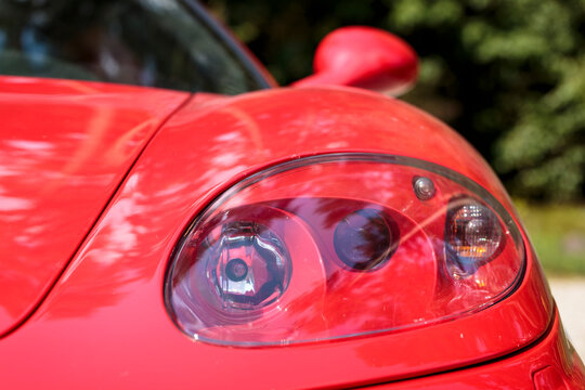 Headlight closeup detail of a famous red Italian supercar. Rosso corsa is the red international motor racing colour of cars entered by teams from Italy	