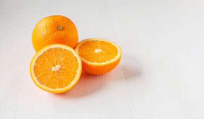 Halved orange fruit on white wooden background