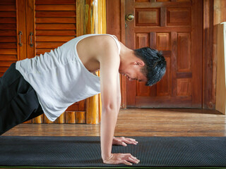 Exercise and Health Asian teenage boy Exercise Push-ups on a yoga mat at home.อ