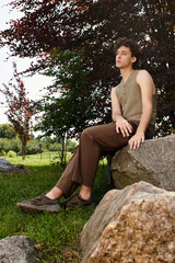 Young man enjoys a sunny day in a stylish summer outfit in a vibrant green park