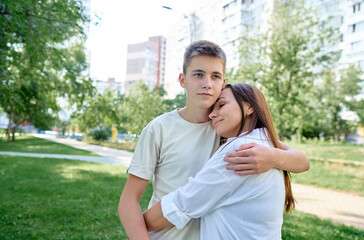 Mother and Son Hugging Outdoors in a Sunny Urban Park