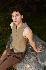 Curly-haired young man enjoys a summer day in a vibrant green park outdoors
