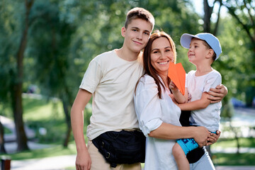 A happy mother shares joy with her young sons on a sunny day at the park. The setting features...