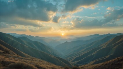 Sunset over mountain valleys with clouds and distant hills, capturing the serene landscape.