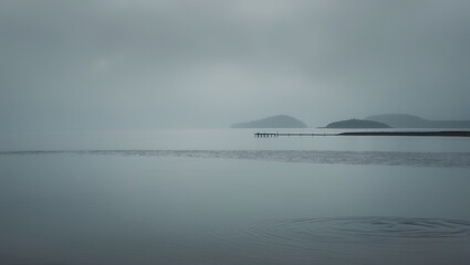 Calm water scene with distant islands under overcast sky. Peaceful landscape with subtle ripples. Tranquil nature, moody atmosphere, and horizon view.