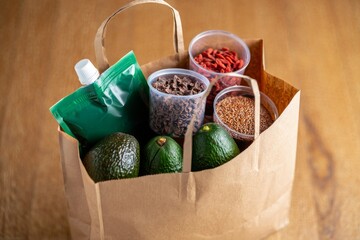 Healthy groceries including avocados and dried beans in a paper shopping bag