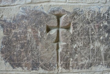 Historical engravings depict a cross on a rustic stone wall at an archaeological site