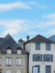 Old buildings with triangular rooftops and shutters stand tall beneath a vibrant blue sky