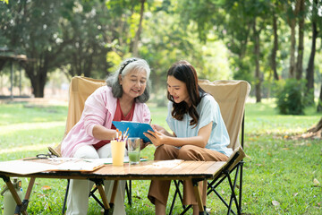 A senior mother and her daughter spend quality time together outdoors, sharing a tender moment...