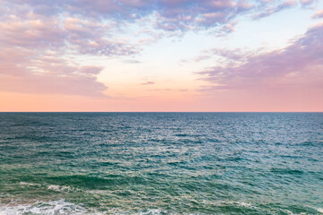 Aerial view of a tranquil ocean reflecting the soft hues of the pastel sky at dusk, Kingsbridge, England, United Kingdom.