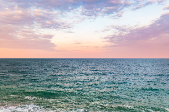 Aerial view of a tranquil ocean reflecting the soft hues of the pastel sky at dusk, Kingsbridge, England, United Kingdom. - Powered by Adobe