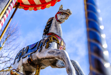 Vintage carousel horse stands ready for children at a lively fairground during a sunny afternoon in a charming town square