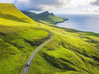A car drives along a winding road surrounded by vibrant green hills overlooking the coastline. The bright sky hints at a clear day, perfect for an adventurous journey.