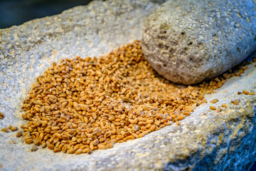 Grinding techniques used for processing grains in a traditional setting featuring stone tools and wheat seeds