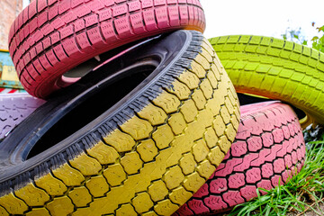 Colorful stack of used tires arranged in a garden setting enhancing the vibrant atmosphere during a...