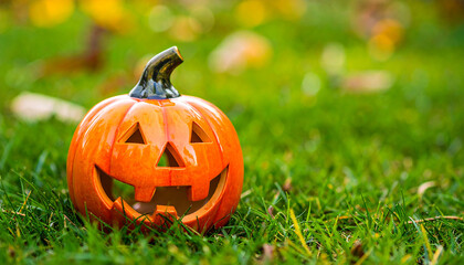 Obraz premium Ceramic pumpkin for Halloween on green grass lawn. Autumn holiday. Fall season.