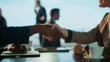 A business deal is sealed with a handshake. Diverse individuals in suits are present, suggesting a professional setting. - Powered by Adobe