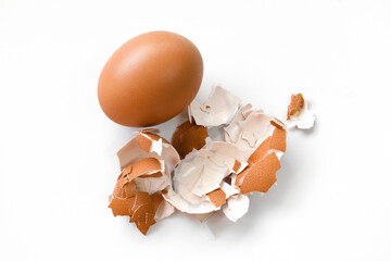 Brown egg and eggshell on white. Benefits of eggshell concept.