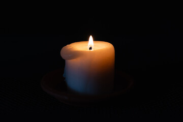 A burning candle in the darkness. Selective focus,black background.