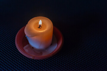 A burning candle in the darkness. Selective focus,black background.