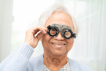 Optometrist checking Asian elderly woman ophthalmic vision eye test and using optical trial frame.