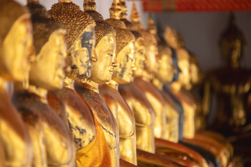 Row of golden Buddhas in the cloister of one of the Buddhist temples of Wat Phra Chetuphon - Wat Pho in Bangkok, Thailand.