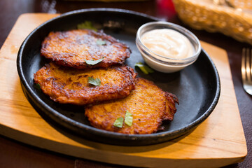 Potato pancakes with sour cream on frying pan