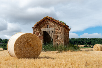 petite maison en pierre ancienne au milieu de champs de bl&eacute; avec une grosse botte de paille par une belle journ&eacute;e d'&eacute;t&eacute; proche d'Issoire dans le puy de D&ocirc;me